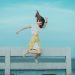 Jumpshot Photography of Woman in White and Yellow Dress Near Body of Water